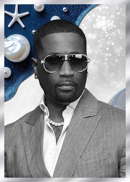 A Black man wearing sunglasses and a gray suit stands in front of a starry blue background with various celestial objects.