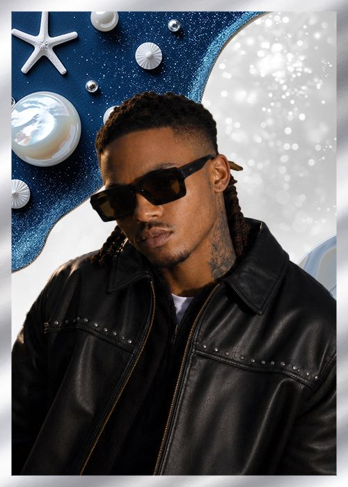 A man wearing sunglasses and a black leather jacket stands in front of a sparkling blue and white background with starfish and shells.