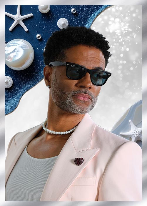 A man wearing sunglasses and a pink suit stands in front of a starry blue background with seashells and other ocean-themed objects.