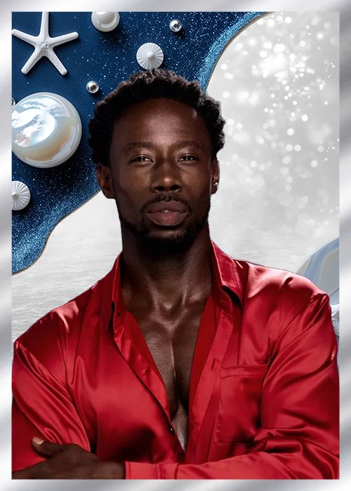 A man with a beard wearing a red satin shirt stands in front of a starry blue background with seashells and other ocean-themed objects.